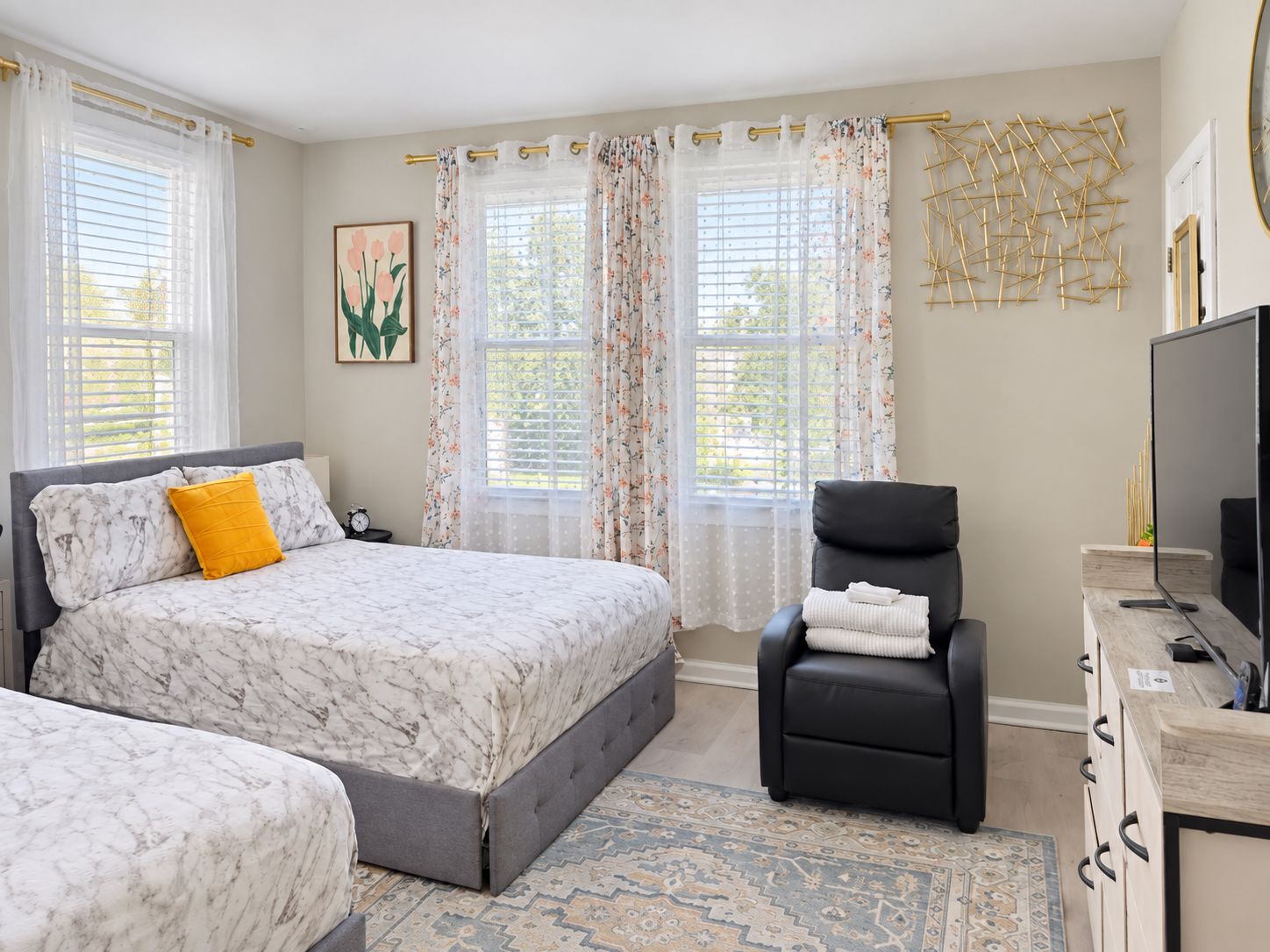 A bedroom with a bed, a chair, a television, and a desk.