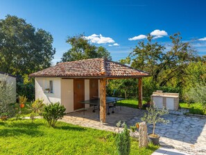 Una casita con techo de tejas, un jardín con macetas y un patio de piedra.