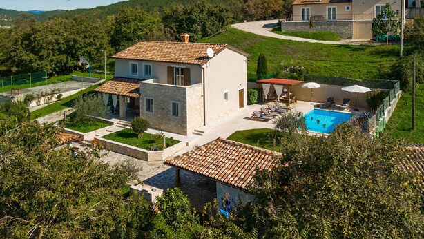 Una casa a due piani con piscina, immersa nel verde e circondata da colline.