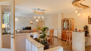Un'ampia sala da pranzo con una parete di pietra a fare da sfondo, una televisione e un mobile in legno con ante in vetro.