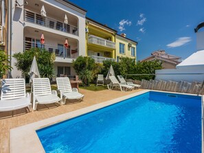A swimming pool with lounge chairs, a building with balconies, and a clear blue sky. - ABERT SUSI / HR-05640-01 by Interhome (Novi Vinodolski)