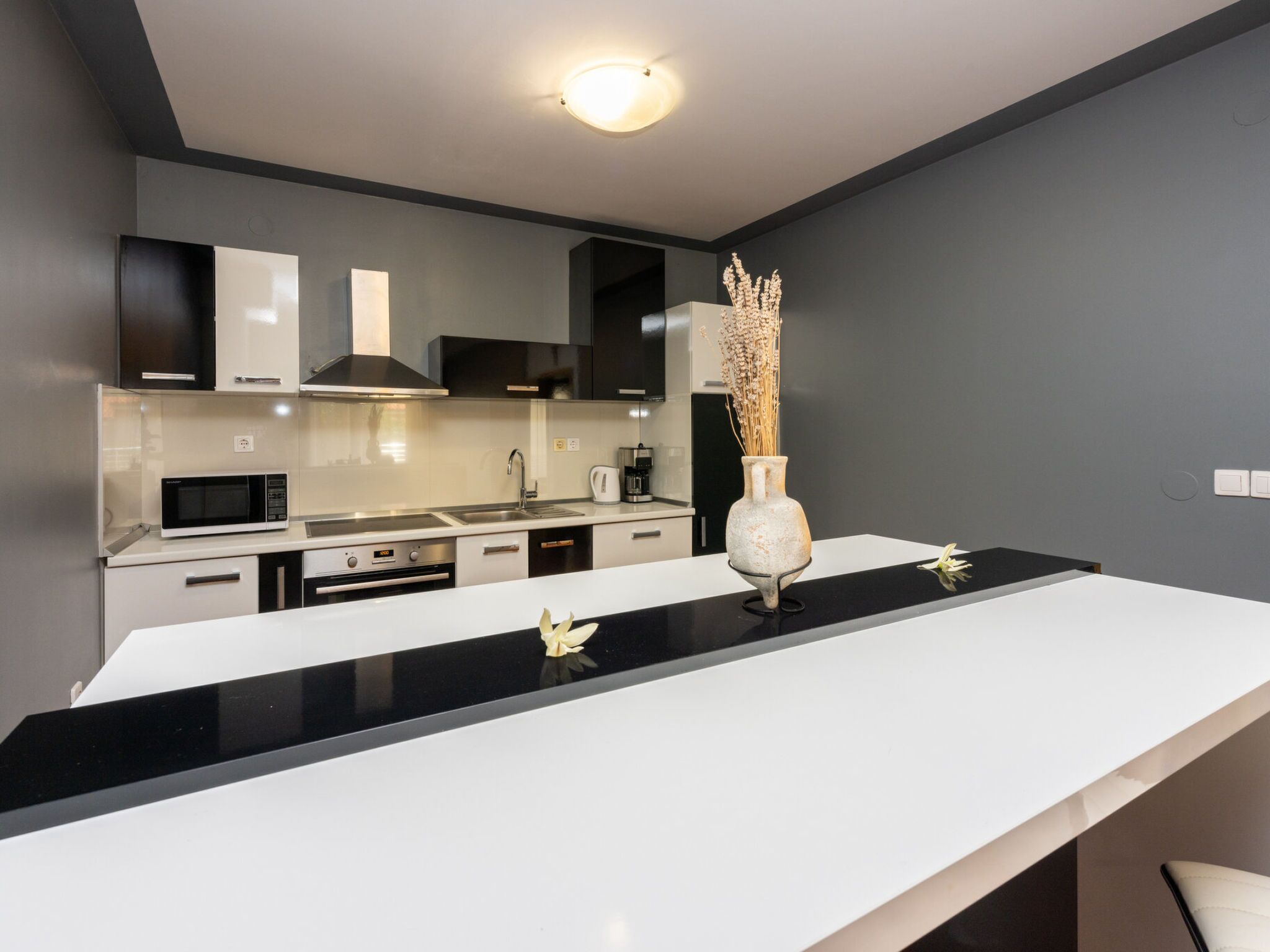 A modern kitchen with a black countertop, white cabinets, and a stainless steel range hood.