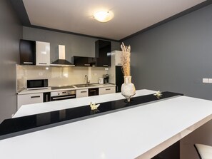 A modern kitchen with a black countertop, white cabinets, and a stainless steel range hood. - ABERT SUSI / HR-05640-01 by Interhome (Novi Vinodolski)