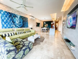 Ein modernes Wohnzimmer mit einem grünen Sofa, einem Couchtisch und einem großen abstrakten Gemälde an der Wand.
