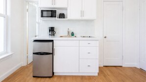 A compact kitchen with white cabinets, a stainless steel refrigerator, a microwave, and a coffee maker. - Miami Beach Studio Quiet Oasis (Miami Beach)