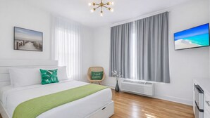 A modern hotel room with a bed, a chair, a TV, and a window with curtains. - Miami Beach Studio Quiet Oasis (Miami Beach)