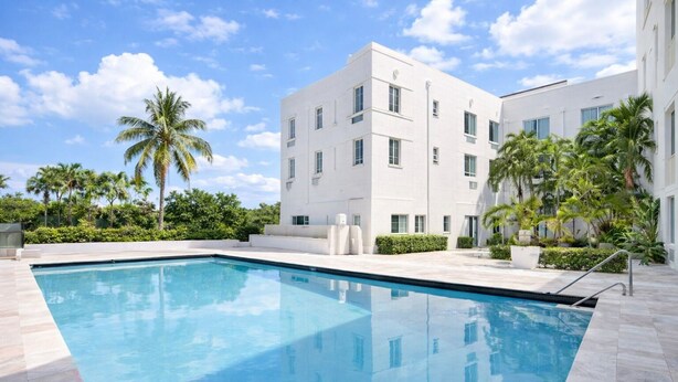 A modern building with a swimming pool, surrounded by palm trees and greenery. - Miami Beach Studio Quiet Oasis (Miami Beach)