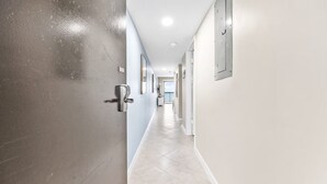 Un pasillo con una puerta a la izquierda, un interruptor de luz en la pared y un accesorio de iluminación en el techo.