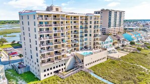 Un hotel de varios pisos con balcones, un área de piscina y vistas del paisaje circundante.