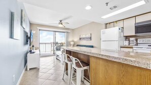 Una cocina moderna con barra, ventilador de techo y vistas al exterior.