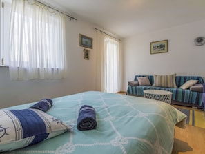 Ein Schlafzimmer mit einem Bett, einem Schlafsofa, einem kleinen Tisch und zwei Wanduhren.
