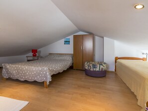 Ein Schlafzimmer mit Bett, Kleiderschrank, einem kleinen Tisch mit Lampe und einer Bank.