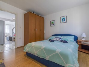 Ein Schlafzimmer mit einem Bett, einem Kleiderschrank und zwei gerahmten Bildern an der Wand.