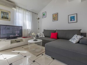 A modern living room with a grey sofa, a TV, and artwork on the walls. - STIVIC 2 / HR-08046-01 by Interhome (Selce)