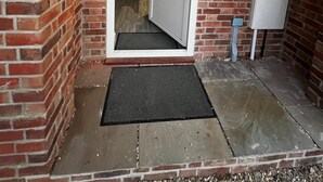 Facciata in mattoni con una porta che dà su un corridoio, una cassetta postale e un numero civico.