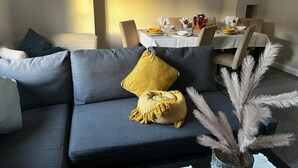 Un soggiorno moderno con un divano grigio, un cuscino giallo e una pianta decorativa.