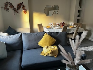 A modern living room with a grey sofa, a yellow throw pillow, and a decorative plant. - 2 Modern Homes | Free Parking | Thetford (Thetford)