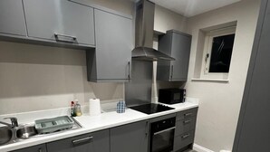 Una cucina moderna con mobili grigi, un lavello in acciaio inossidabile e un forno integrato.
