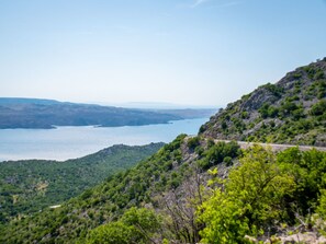 Eine Küstenlandschaft mit einer kurvenreichen Straße, die sich durch Hügel schlängelt und auf ein großes Gewässer blickt.