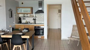 Une cuisine de taille réduite comprenant un coin repas, un escalier et une porte donnant sur une autre pièce.