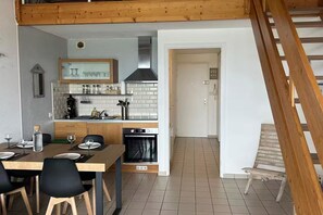 A compact kitchen with a dining area, a staircase, and a door leading to another room. - Apartment, breathtaking sea view (bed linen and towels included) (Saint-Gilles-Croix-de-Vie)