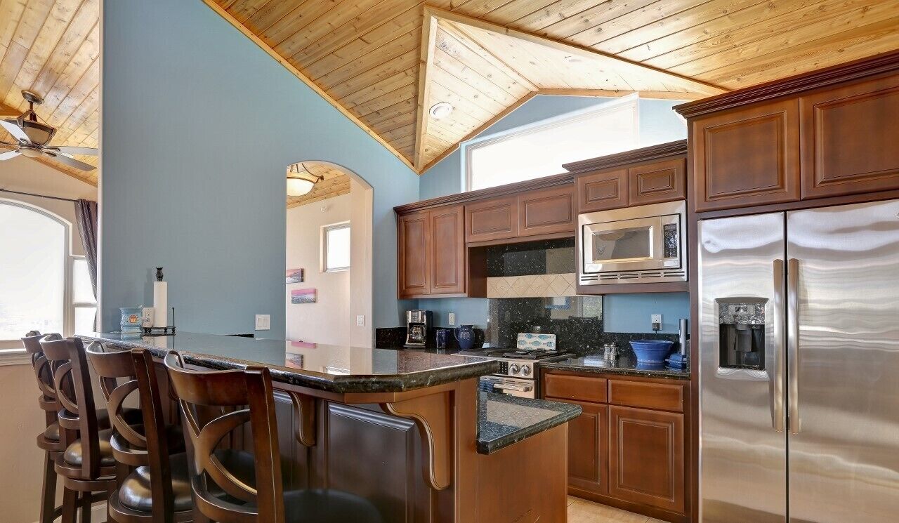 A kitchen with wooden cabinets, a stainless steel refrigerator, a microwave, and a stove.