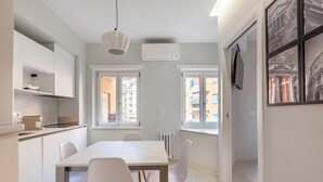A modern kitchen with white cabinets, a dining table with chairs, and large windows. - A Romantic Roman Getaway: Elegant Apartment Steps from the Vatican (Roma)