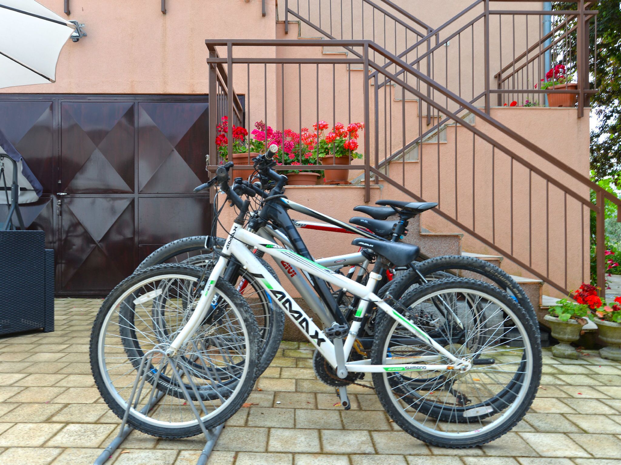A bicycle parked in front of a building with a staircase and potted plants.