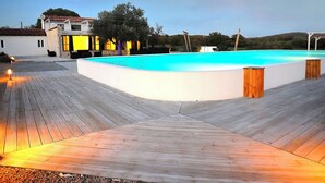 A swimming pool with a wooden deck, a building with yellow-lit windows, and a clear sky. - Villa Mojito by Interhome (Rovinj)