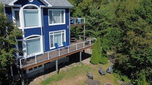 A two-story house with a balcony, surrounded by trees. - Bleuzen • Vue splendide • 2 chambres • Foyer • Balcon (Petite-Rivière-Saint-François)