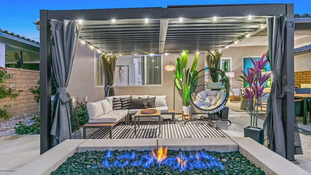 An outdoor patio with a fire feature, seating, and potted plants. - Golf n Grooves. Luxury La Quinta Villa. (La Quinta)