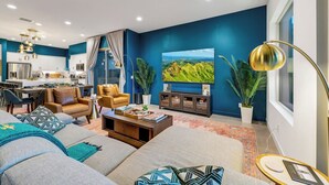 A modern living room with a sofa, coffee table, and a dining area with a kitchen in the background. - Golf n Grooves. Luxury La Quinta Villa. (La Quinta)