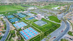 An aerial view of a resort with multiple swimming pools, a golf course, and a road curving around the property. - Golf n Grooves. Luxury La Quinta Villa. (La Quinta)