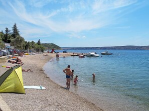 A beach with a tent, people relaxing, and boats in the water. - Tereza / HR-09066-01 by Interhome (Crikvenica/Jadranovo)