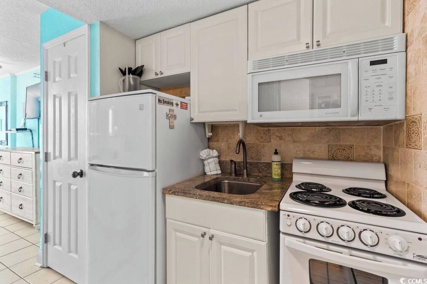 A kitchen with white cabinets, a refrigerator, a microwave, and a stove.