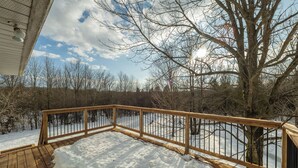 A wooden deck with snow accumulation, surrounded by bare trees and a clear sky. - The Bognor House (Meaford)
