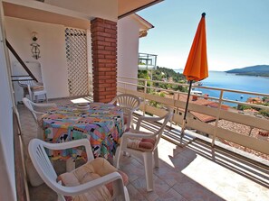 A balcony with a table, chairs, and an umbrella overlooking a coastal view. - Apartment 155 by Interhome (Rabac)