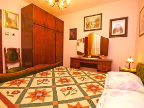 A bedroom with a large bed, a wooden wardrobe, a desk with a mirror, and a chair. - Apartment 155 by Interhome (Rabac)