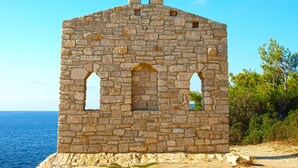 A stone structure with arched openings, situated by the sea. - Apartment 63 by Interhome (Pula)