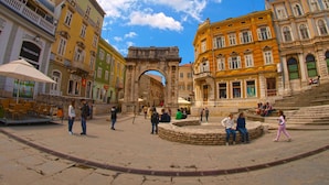 A historic square with an archway, surrounded by buildings with balconies and shops. - Apartment 63 by Interhome (Pula)