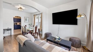 Ein Wohnzimmer mit einer Couch, einem Couchtisch, einem Fernseher und einem Essbereich mit Stühlen und einem Tisch.