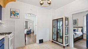 Eine moderne Küche mit Gaskochfeld, ein Essbereich mit blauem Sofa und ein Schlafzimmer mit Bett und Fensterläden.