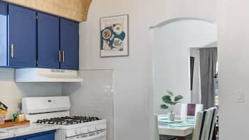 Une cuisine avec des meubles bleus, une cuisinière blanche et un lustre.