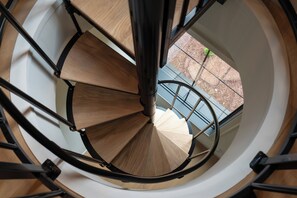 A spiral staircase with wooden steps and metal railings, leading to an outdoor area with a blue railing.