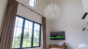 Ein Schlafzimmer mit großem Fenster, einem Gemälde an der Wand und einem modernen Kronleuchter.