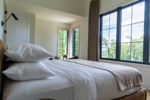 A bedroom with a bed, a window, and a door.