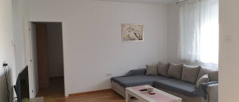 Ein Wohnzimmer mit einem grauen Sofa, einem weißen Couchtisch und einem Holzboden.