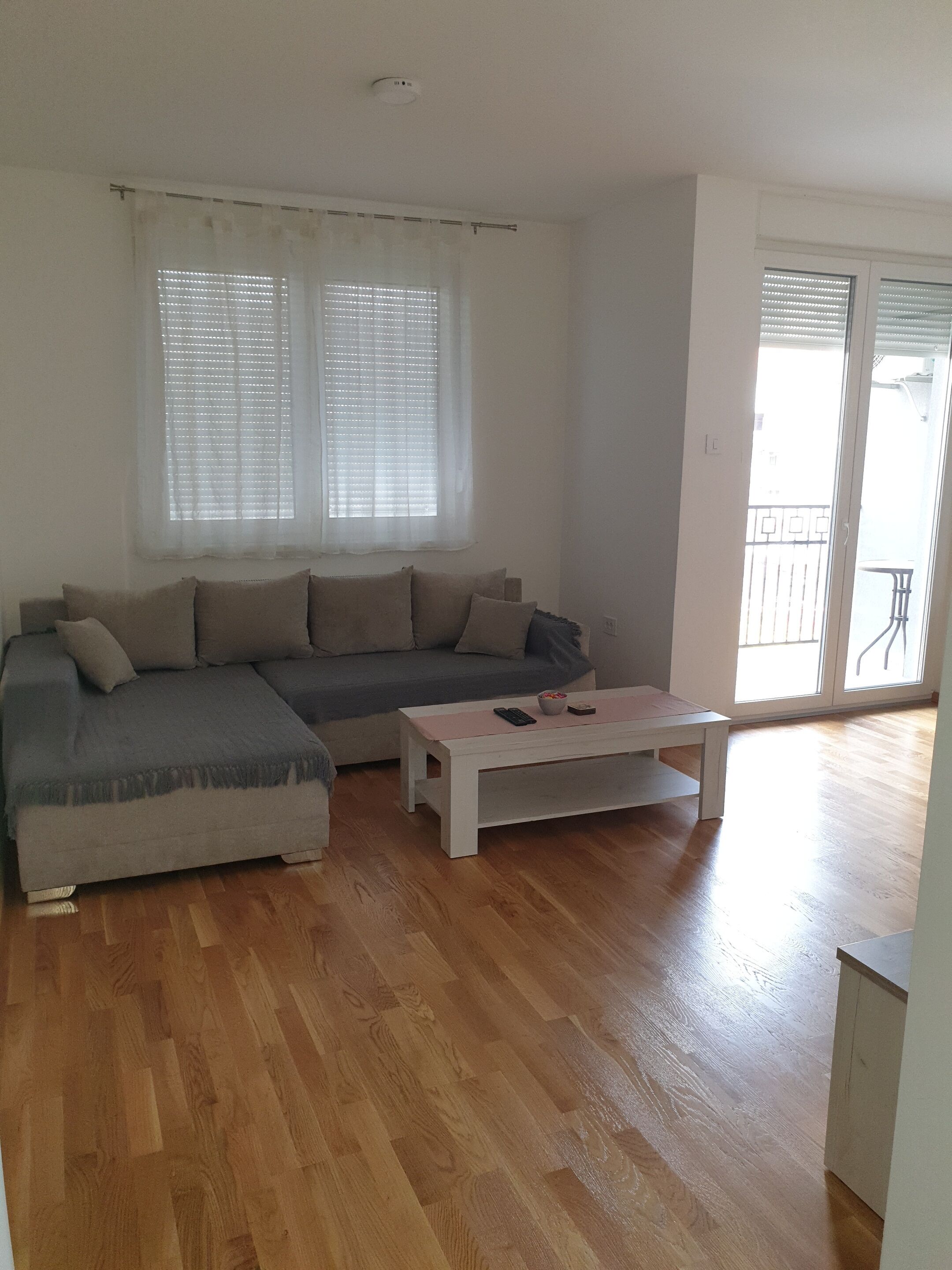 Una sala de estar con sofá, una mesa de centro y un balcón con barandilla.