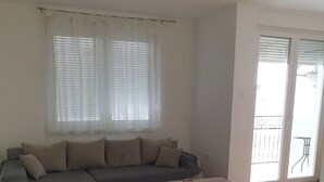 Een woonkamer met een bank, een salontafel en een balkon met een hekwerk.