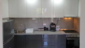 Una cocina moderna con electrodomésticos de acero inoxidable, horno empotrado y cafetera.